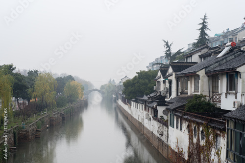 Canal in Suzhou lined by trees and traditional buildings