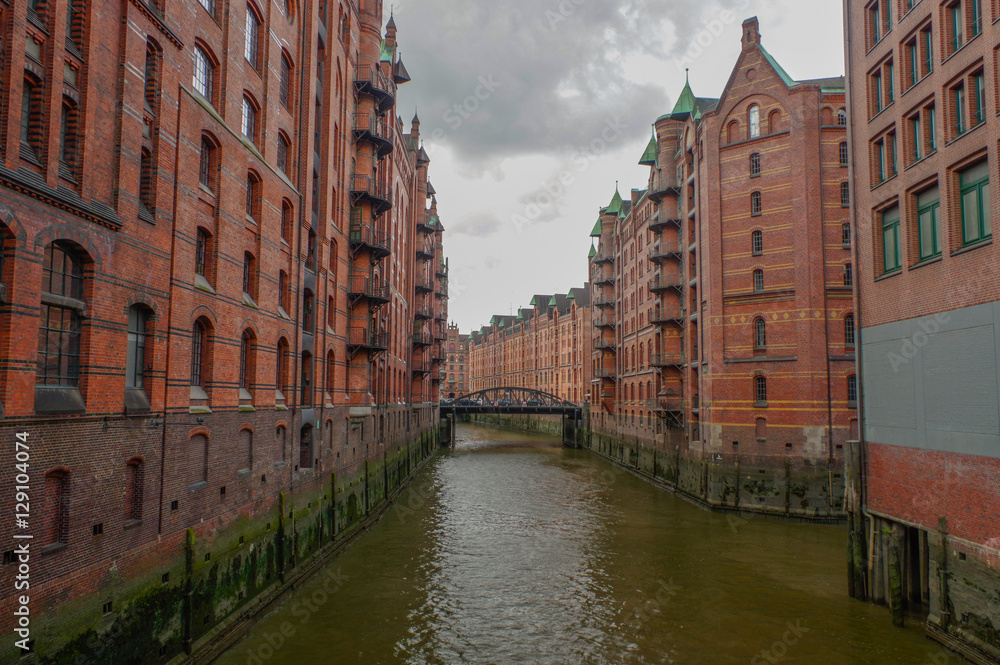 HAMBURG, GERMANY - JULY 18, 2015: the canal of Historic Speicherstadt houses and bridges at evening with amaising skyview over warehouses, famous place Elbe river.
