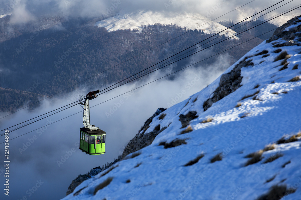 Cable car between mountains with clouds in background