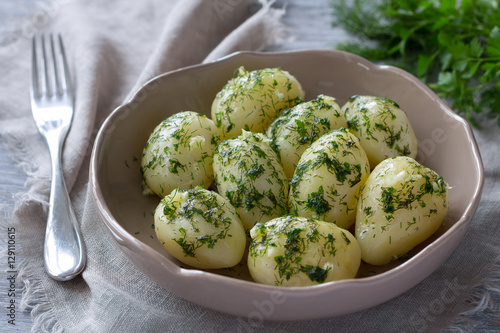 Boiled potatoes with herb butter and garlic on the wooden table, selective focus