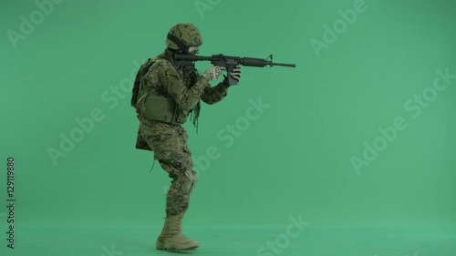 Soldier going and targeting at the camera at green screen