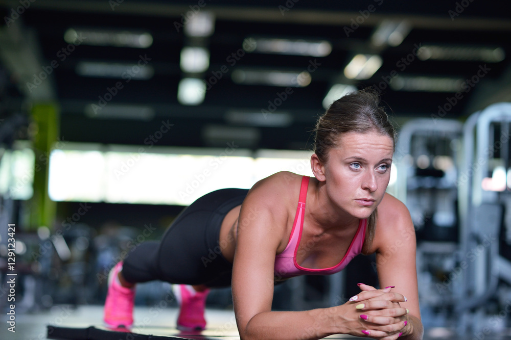 Shot of a fit young woman doing stretching workout on the gym floor. Shot of a fit young woman doing stretching workout on the gym floor.