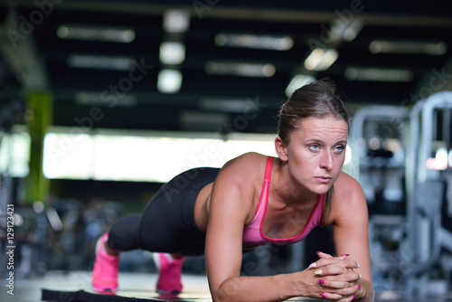 Shot of a fit young woman doing stretching workout on the gym floor.