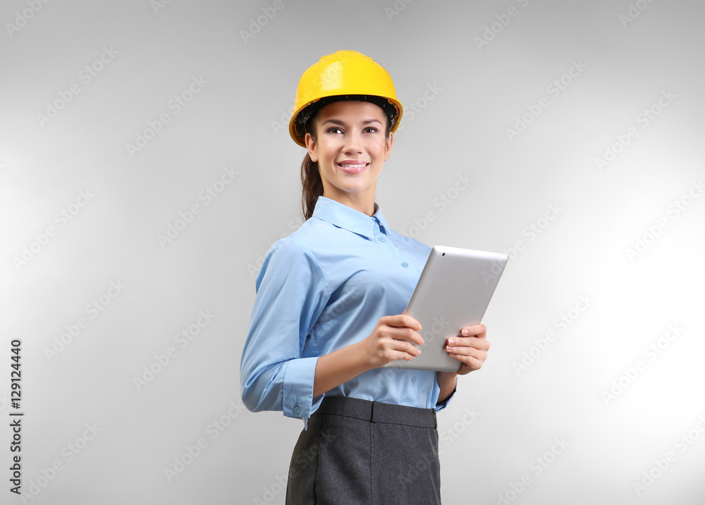 Confident young woman with hardhat and tablet computer, on light background Confident young woman with hardhat and tablet computer, on light background