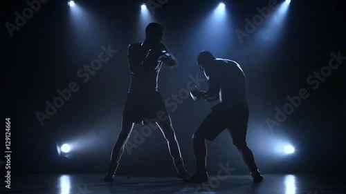 Two young sportsman are boxing in the studio. Slow motion photo