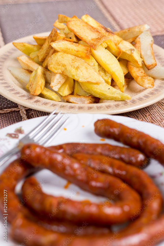 Raw domestic red sausages with fried potatoes Raw domestic red sausages with fried potatoes