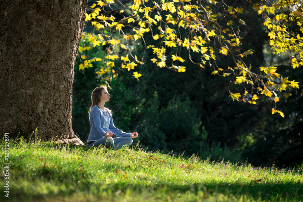 © MIRACLE MOMENTS - Girl meditates sitting on the grass under a maple tree in autumn © MIRACLE MOMENTS - Girl meditates sitting on the grass under a maple tree in autumn