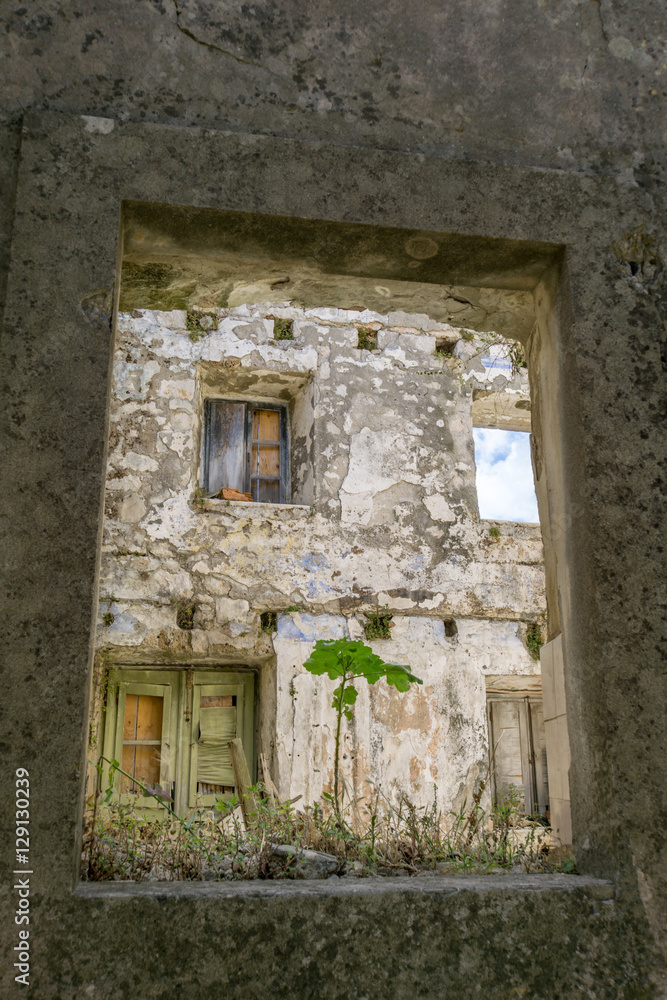 Looking through a window within the surrounding walls of the old town of Mali Ston, Croatia, at a deteriorating medieval house.