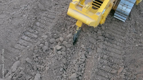 Bulldozer with ripper shank penetrate and loosen the soil on construction site