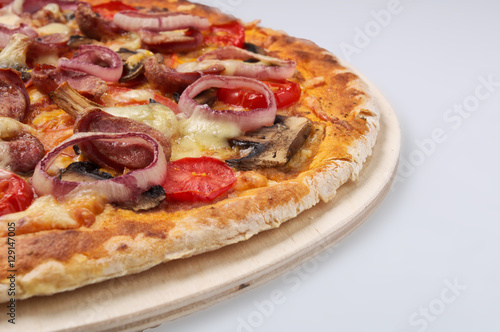 Delicious pizza with sausages and onion on light background