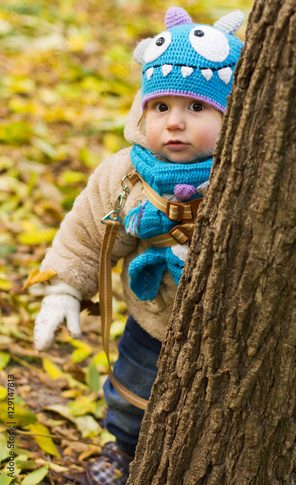 Kid in a funny hat. The boy walks in the fresh air. The kid is playing in the yellow leaves
