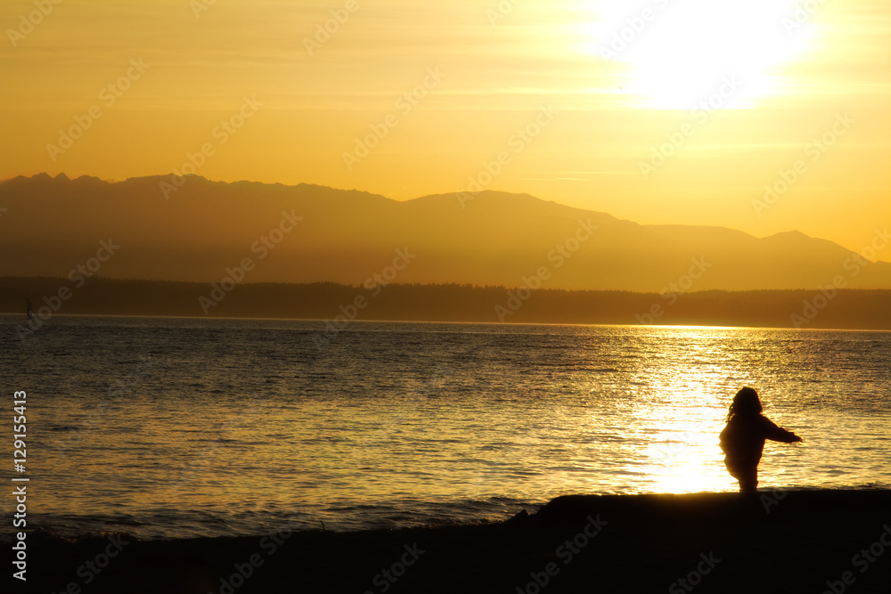 Silhouette of a baby girl playing on the beach at sunset: Golden Gardens Park, Seattle (US)