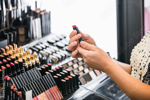 girl chooses red lipstick in store