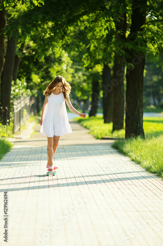 Young girl riding in the park on a skateboard