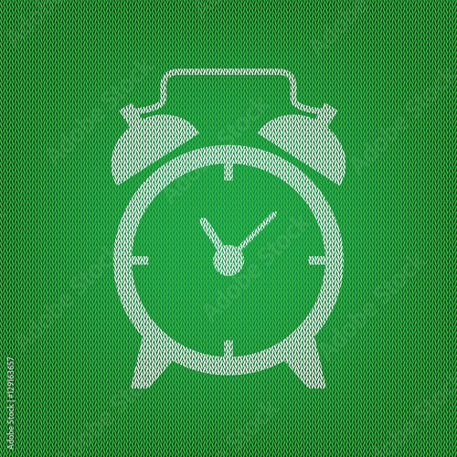 Alarm clock sign. white icon on the green knitwear or woolen clo
