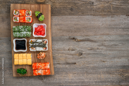 set of sushi and rolls with chopsticks on wooden table
