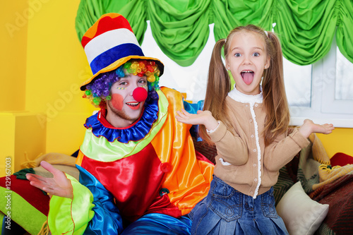 Child girl and clown playing on birthday party.