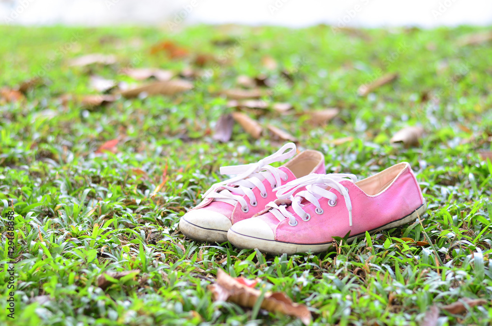 Pink sneakers on a green grass. Rest in the park without shoes.
