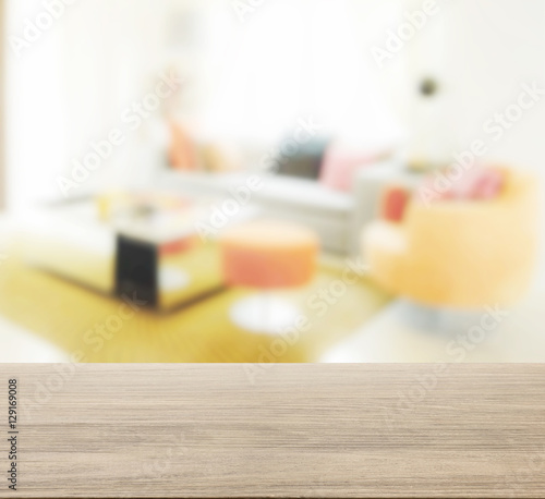 wooden table top with blur of modern living room interior with orange tone decoration