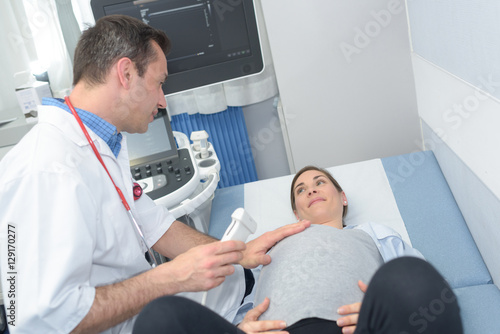 male obstetrician listening the tummy of pregnant woman