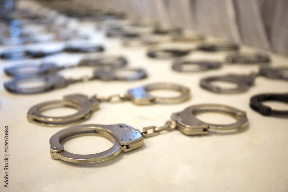 row of law enforcement silver metal handcuffs on white table row of law enforcement silver metal handcuffs on white table