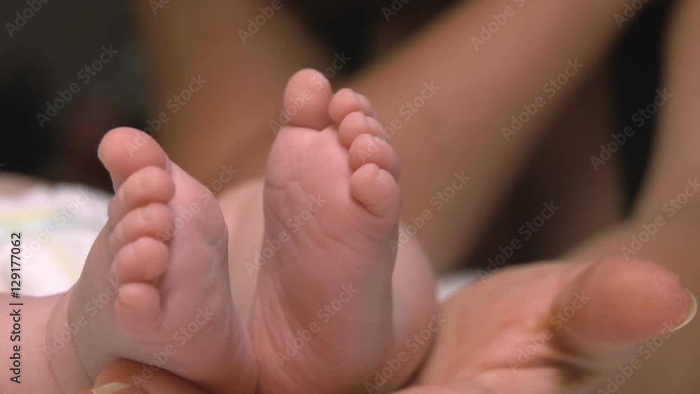 Baby's legs in the hand of an adult