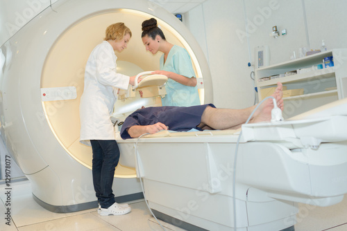 patient on mri machine while two female doctors operating it