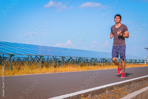 handsome man running on road with solar power plant in morning  Healthy lifestyle with green energy  