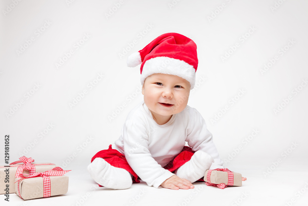 Adorable baby wearing a Santa hat opening Christmas presents Adorable baby wearing a Santa hat opening Christmas presents