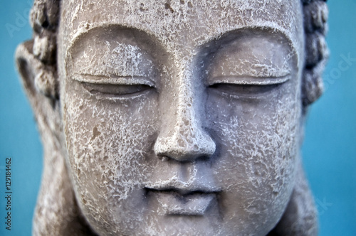 Buddha face on blue background. Close up.
