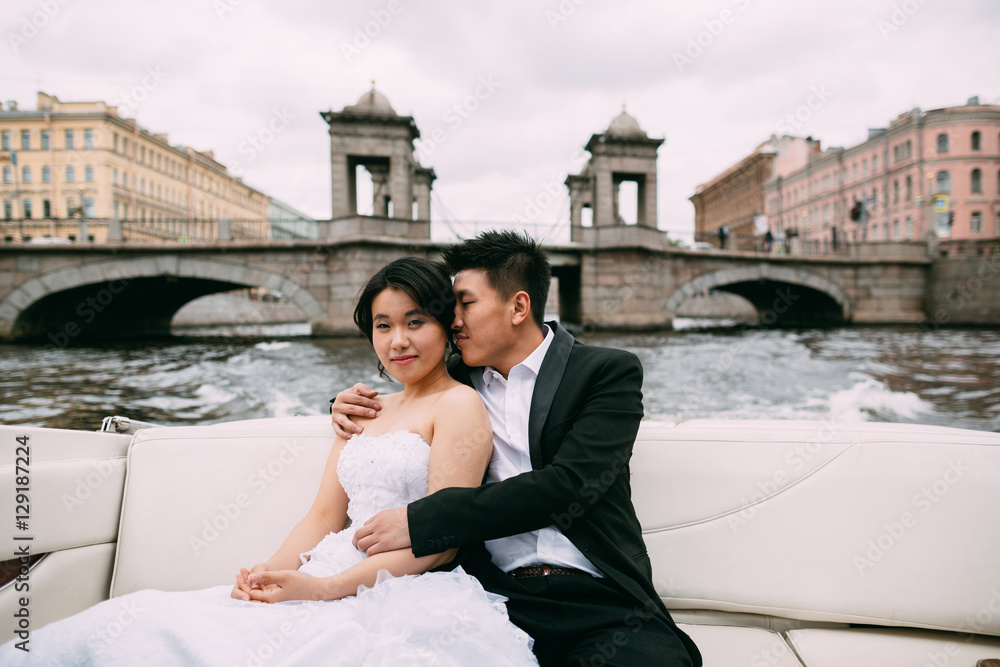 Bride and groom are floating on a boat on the city's rivers and canals Bride and groom are floating on a boat on the city's rivers and canals