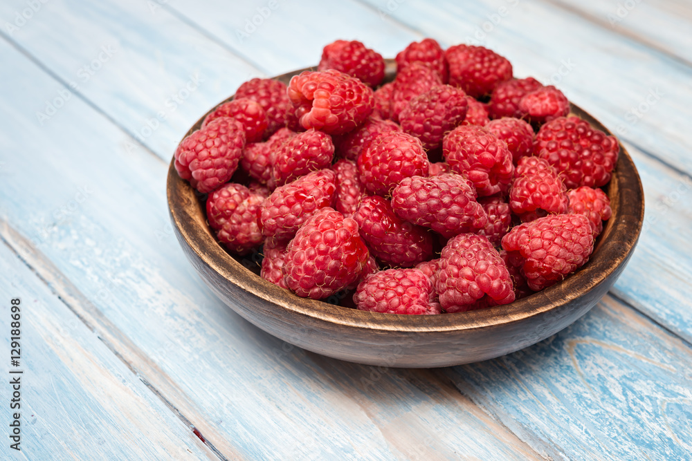 Raspberry in bowl on blue wooden background. Selective focus. Organic food. Raspberry in bowl on blue wooden background. Selective focus. Organic food.