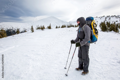 Man hiking in winter mountains before thunderstorm