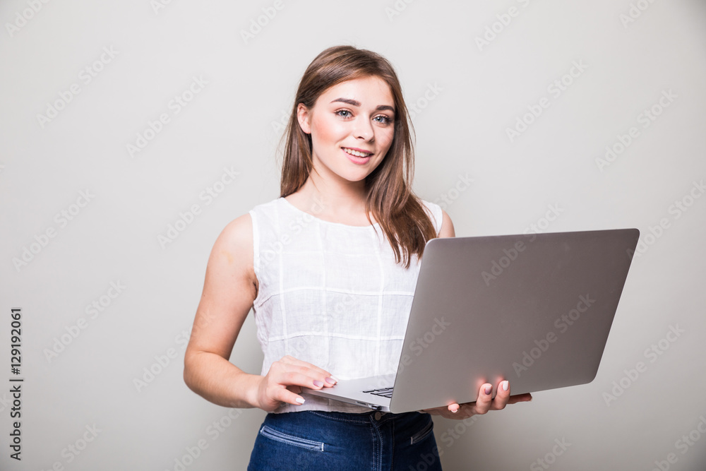 girl standing and using laptop over gray background girl standing and using laptop over gray background