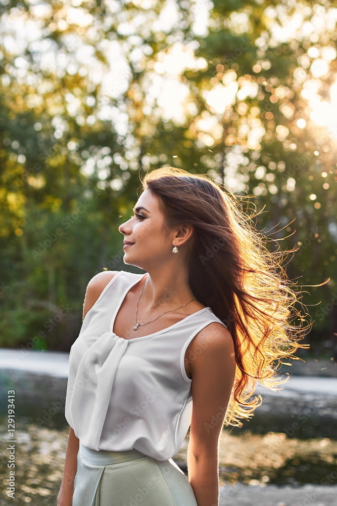 Beautiful girl in elegant dress and charming smile posing for the photographer in the park of Yekaterinburg. Business girl walks after work Beautiful girl in elegant dress and charming smile posing for the photographer in the park of Yekaterinburg. Business girl walks after work
