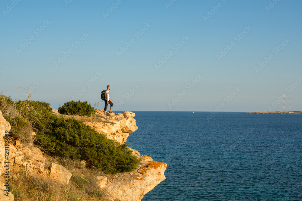 Fototapeta premium Hiker with backpack standing on the rocky cliff