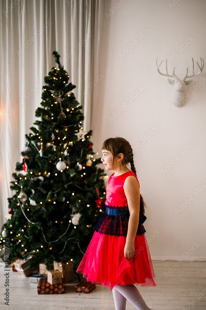 portrait of a girl in a red dress at the Christmas tree