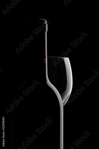 Elegant red wine bottle and wine glass in a black background
