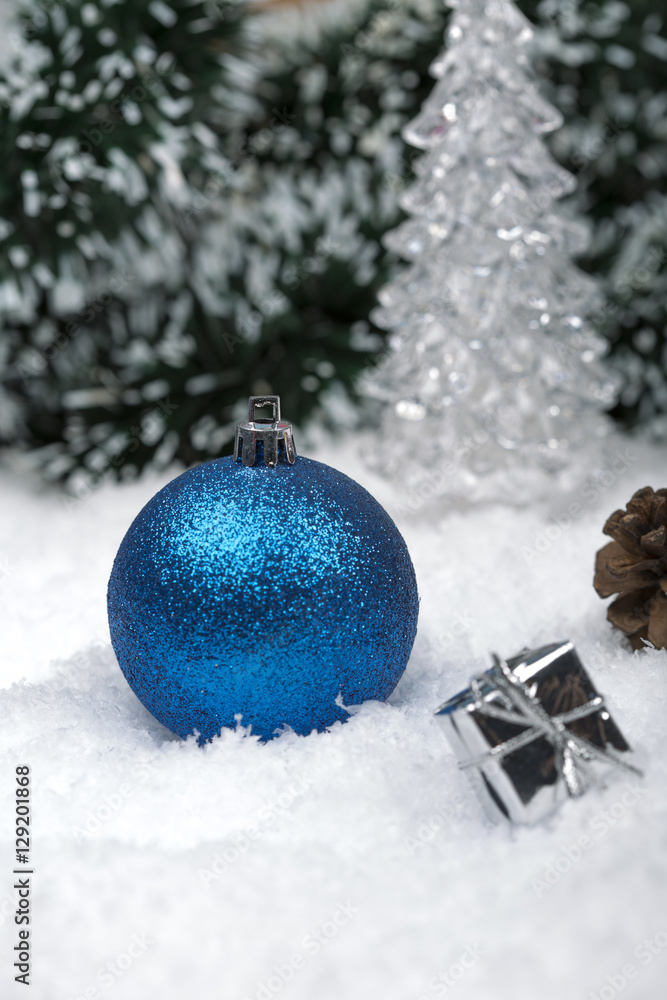 Christmas background with a blue ornament, golden gift box, Angels, berries and fir in snow on forest backround