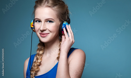 Smiling woman listening to music on headphones on blue backround
