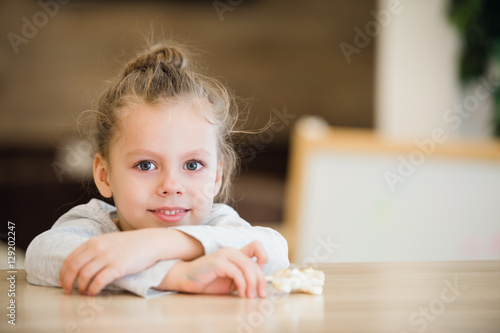 Beautiful calm little girl sitting at wooden table