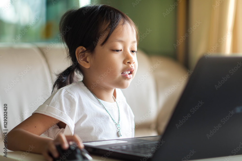 Cute little child smiling and looking at laptop in room at home. Cute little child smiling and looking at laptop in room at home.