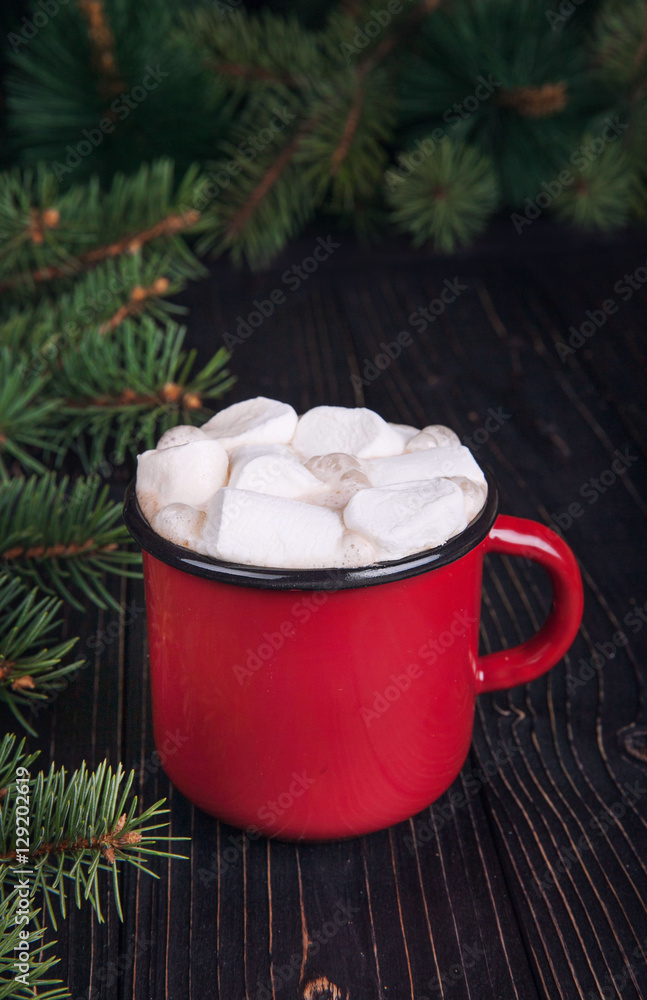 Red enamel cup of hot cocoa with marshmallows on dark wooden bac Red enamel cup of hot cocoa with marshmallows on dark wooden bac