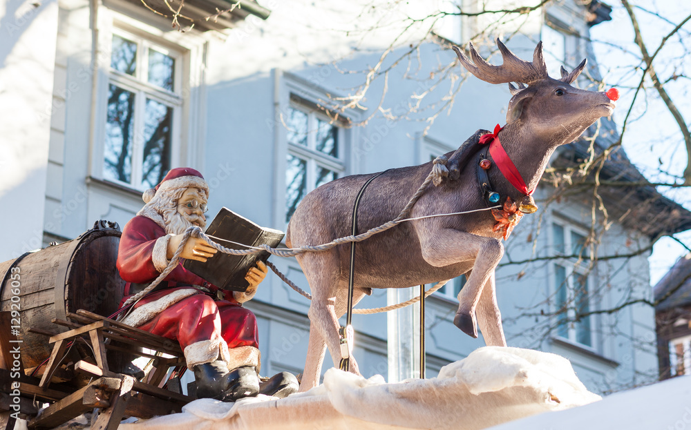 Santa Claus reading a book on the sledge with a reindeer
