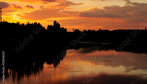 Silhouette of the town at sunset with reflection in the river