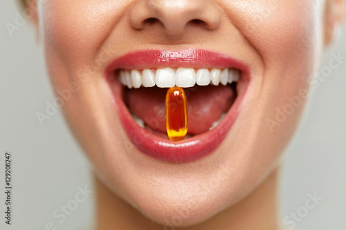 Beautiful Woman Mouth With Pill In Teeth. Girl Taking Vitamins photo