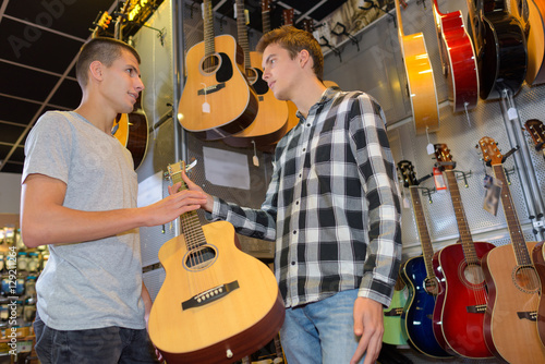 Young men looking at guitar in shop