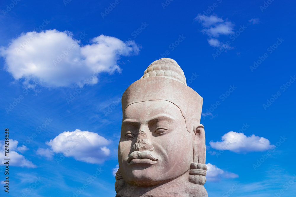 Ancient stone face in Angkor Wat complex on blue sky background, Siem Reap Cambodia Southeast Asia. UNESCO World Heritage Site. Scenic landscape. Popular asian landmark, famous destination of Cambodia