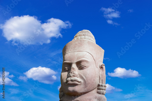 Ancient stone face in Angkor Wat complex on blue sky background, Siem Reap Cambodia Southeast Asia. UNESCO World Heritage Site. Scenic landscape. Popular asian landmark, famous destination of Cambodia