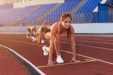 Young woman athlete at starting position ready to start a race.